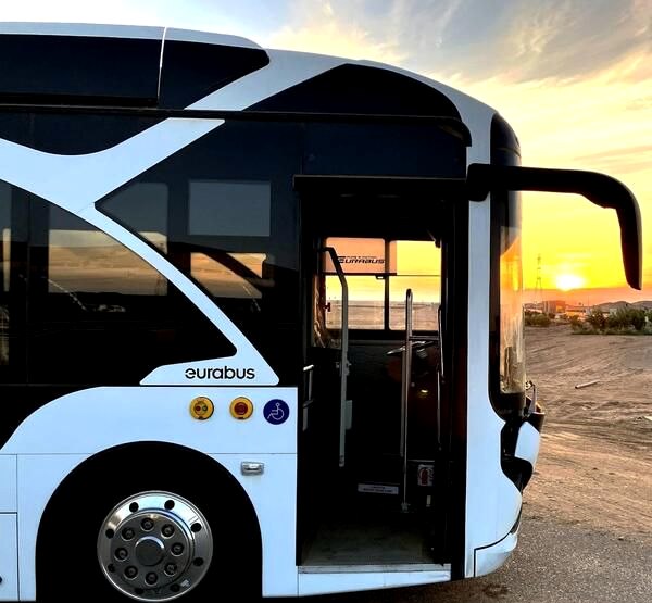 Coach with its door open at golden hour as passengers board